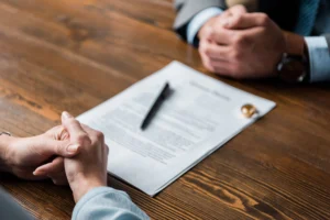 A client and family lawyer reviewing divorce documents during a consultation at a desk, with a wedding ring placed on the paperwork.